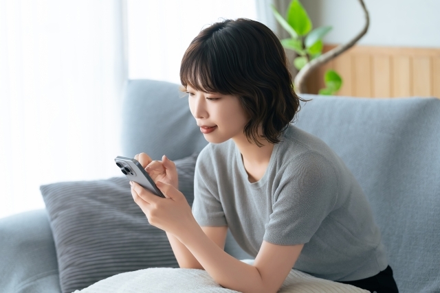 スマホ操作女性ソファ