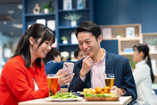 居酒屋でスマを見る男女